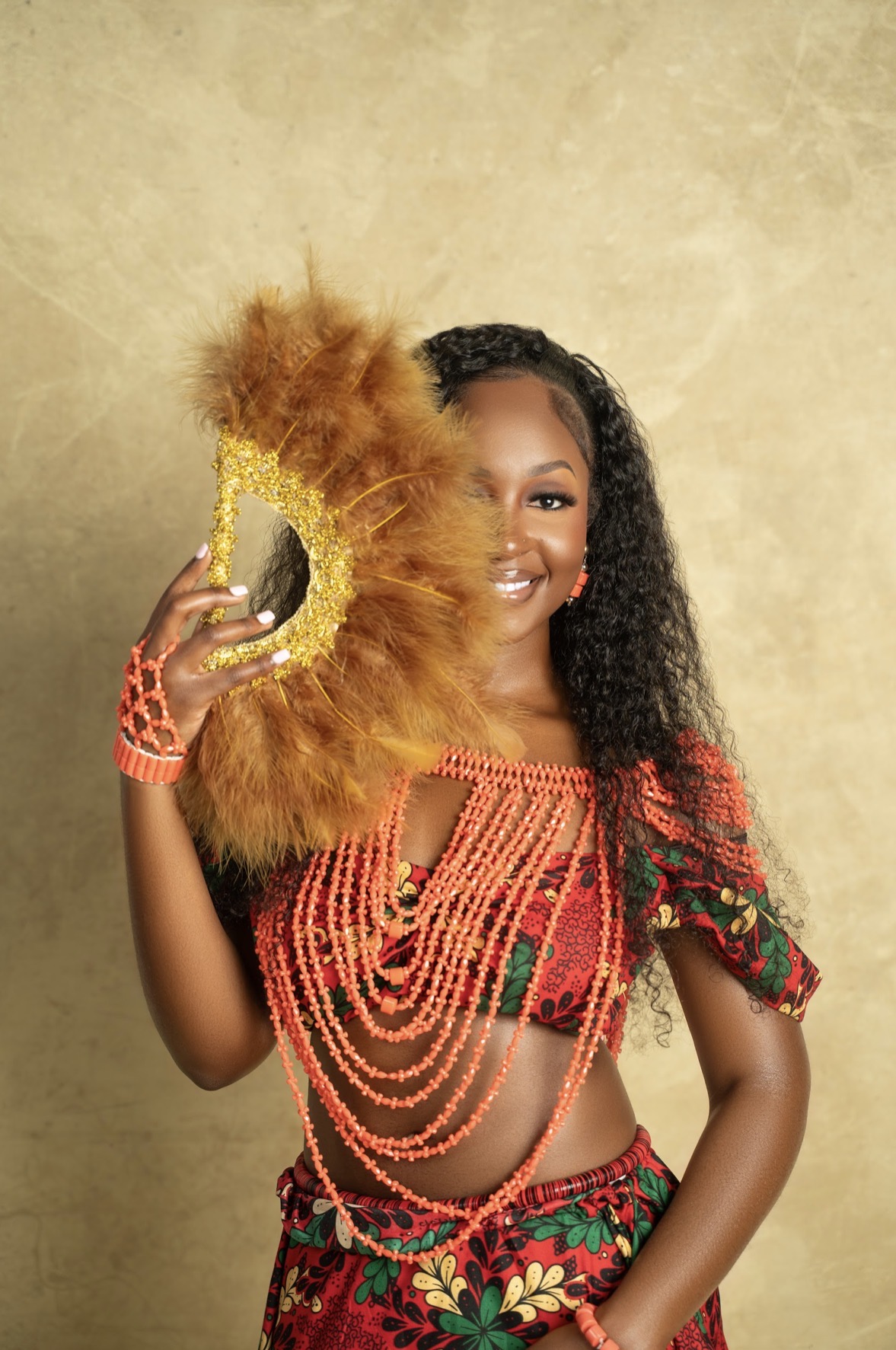 Precious in traditional attire with coral beads and a feather fan